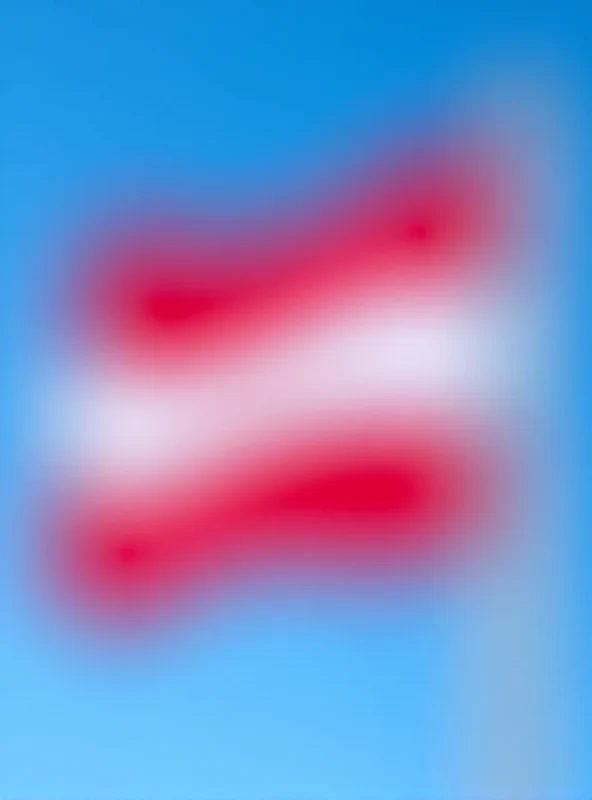 Close-up of the Austrian flag waving in the wind against a clear blue sky.