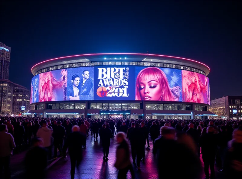 A wide shot of the O2 Arena in London, brightly lit up at night with Brit Awards branding, crowds of people visible.