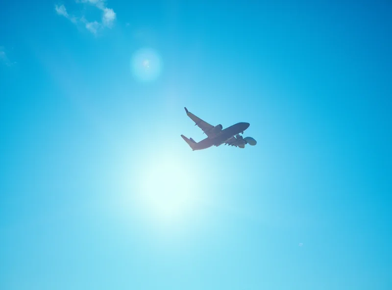 An airplane taking off against a bright blue sky, symbolizing air travel and potential flight delays