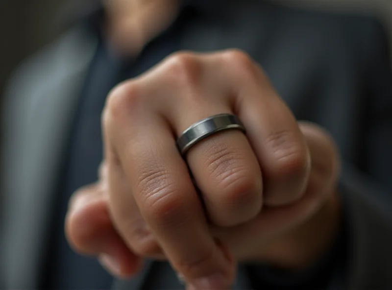 Close up of a hand wearing a Circular Ring 2, showcasing its sleek titanium design. The ring is on the index finger, and the background is blurred to emphasize the ring.