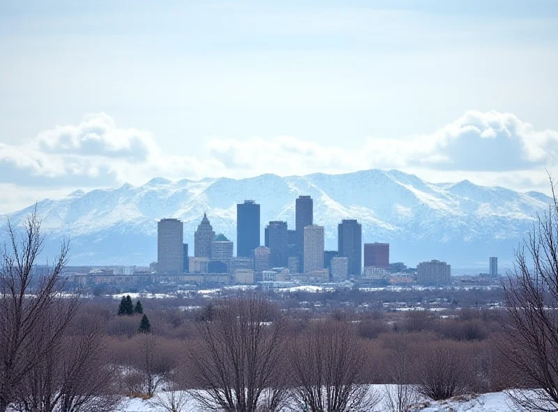 Scenic view of Denver skyline with snow-capped mountains in the background under a partially cloudy sky.