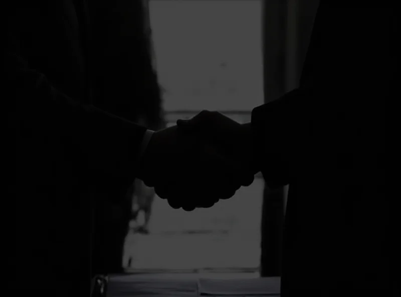 Image of a silhouette of a businessman shaking hands with a politician, suggesting a behind-the-scenes deal and possible corruption.