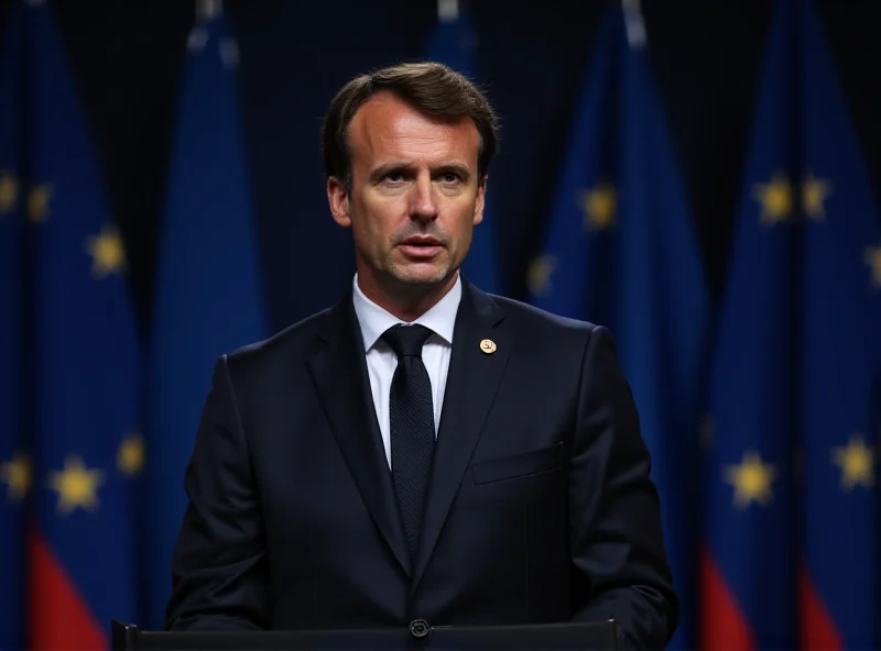 Emmanuel Macron speaking at a podium with a serious expression, European flags in the background.