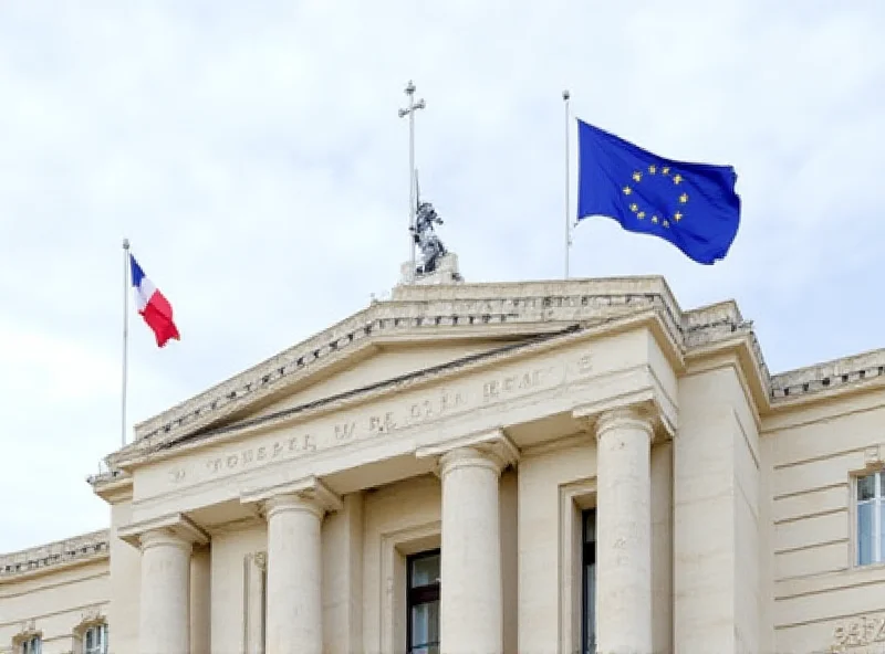 Exterior of a French courthouse with flags flying.