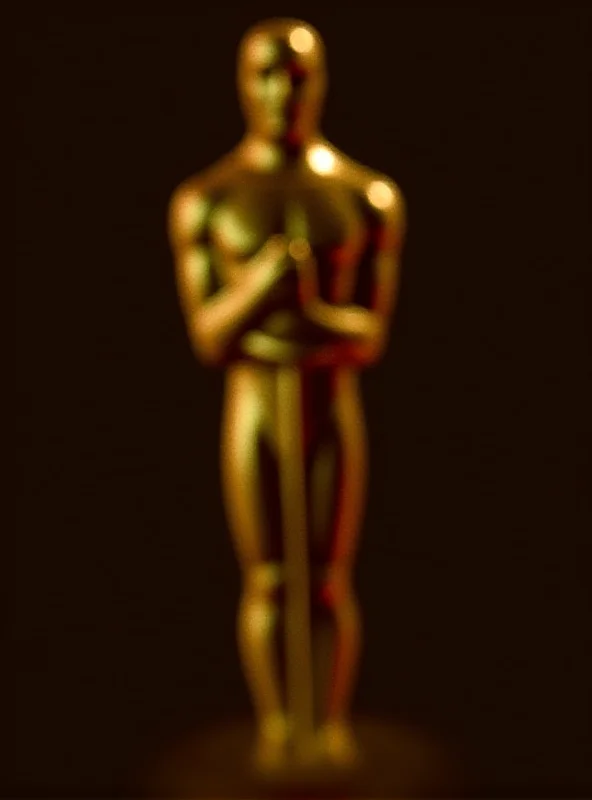 A close-up of a golden Oscar statuette, gleaming under the spotlight.