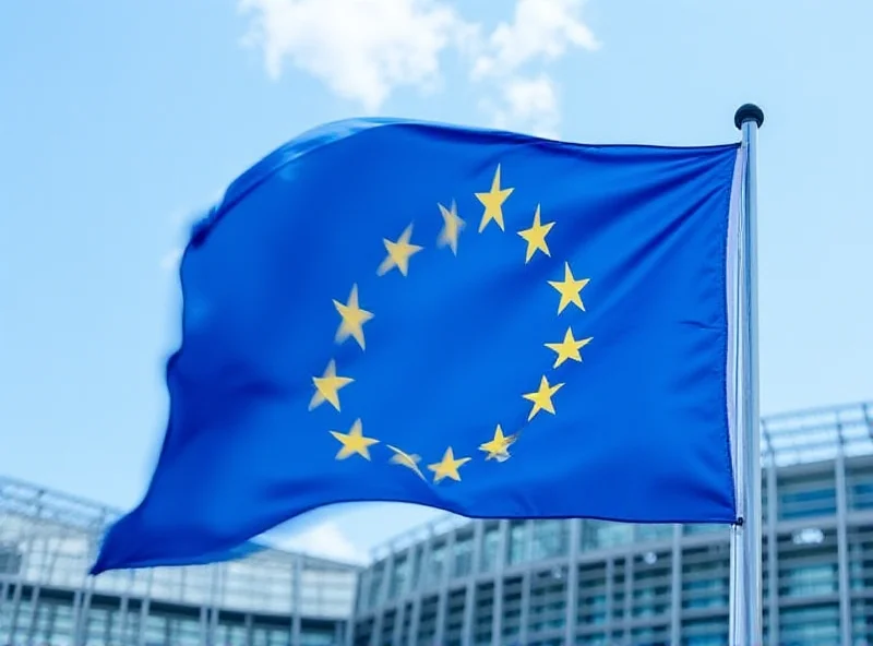 A wide shot of the European Union flag waving in front of the European Parliament building in Brussels.