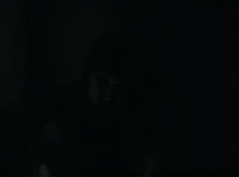 A distressed young woman sitting alone in a dark room, symbolizing the victim of abuse.