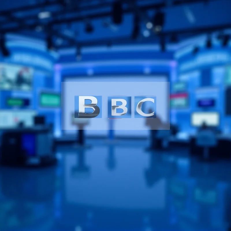 The BBC logo against a blurred background of a news studio.