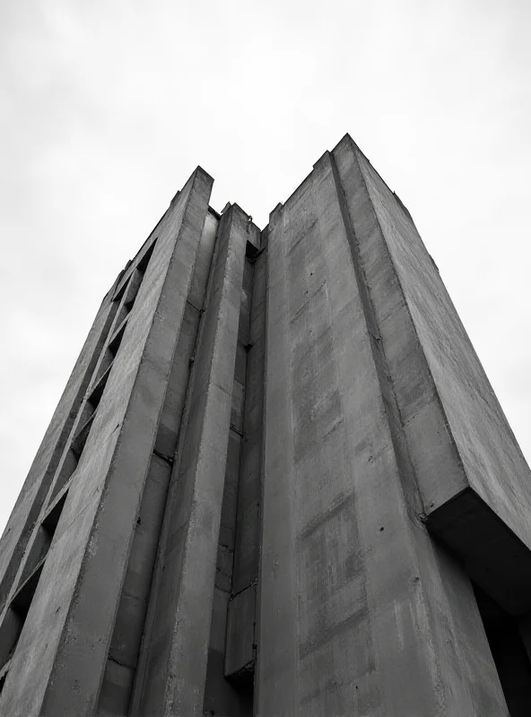 A dramatic shot of a Brutalist building with a cloudy sky in the background.
