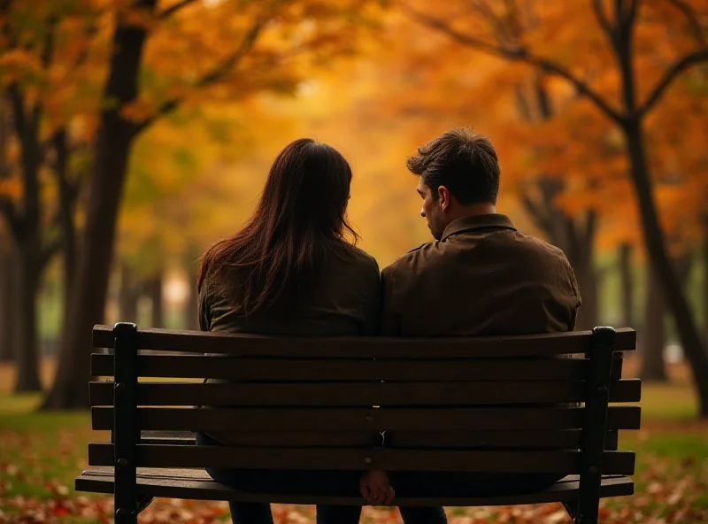 A couple sitting on a bench, looking sadly at each other in a park during autumn.