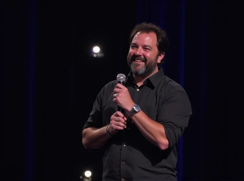 Harith Iskander performing stand-up comedy on stage, holding a microphone and smiling.