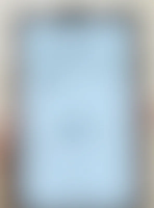 A close-up of a phone screen displaying a social media post with text and images that are blurred to protect privacy, with a notification icon indicating a comment or message.