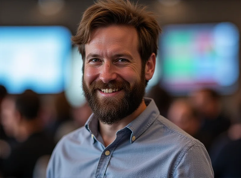 Alexis Ohanian smiling in front of a blurred background of a tech conference.