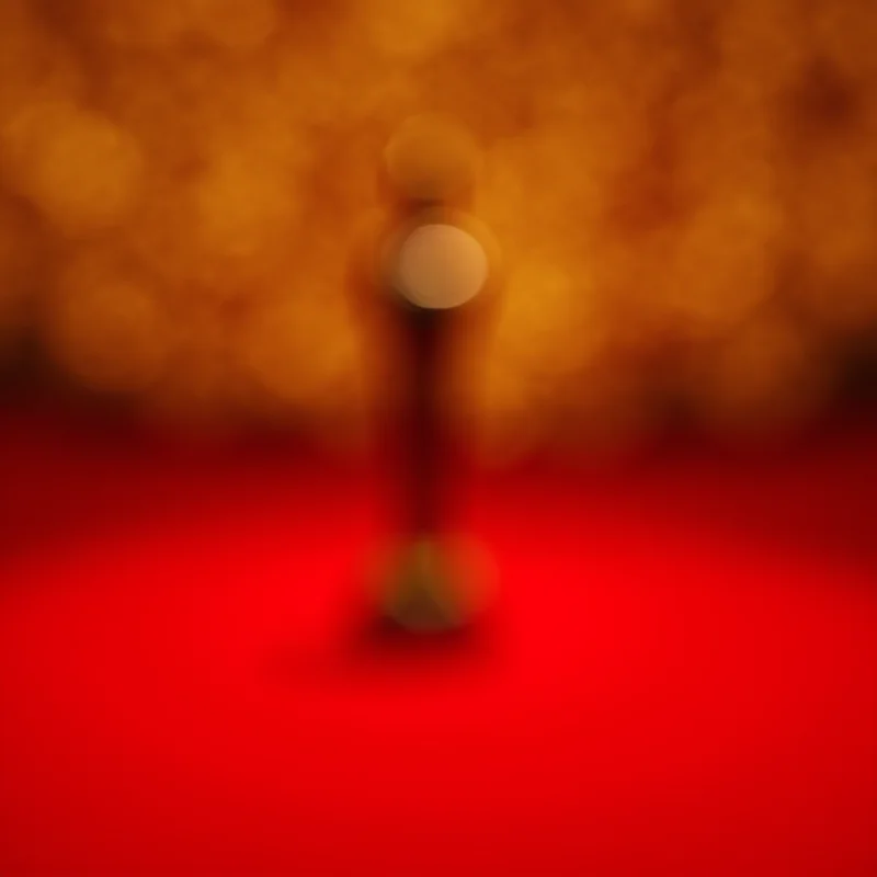 A close-up of a golden Oscar statuette on a red carpet.