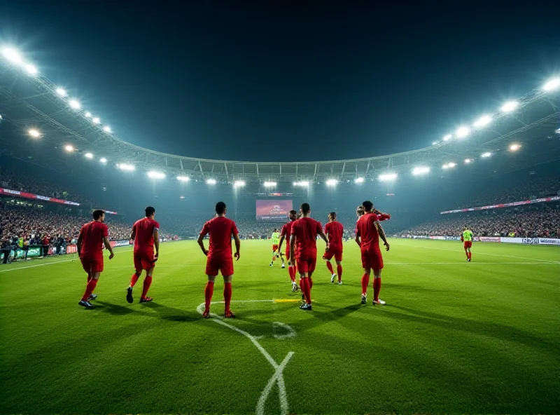 A wide shot of a football stadium during a night match, showcasing the bright lights and the green pitch. A team in red jerseys is celebrating a goal near the corner flag, surrounded by jubilant players and staff.