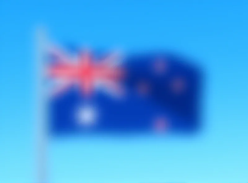 Image of the New Zealand flag waving in the wind against a clear blue sky.