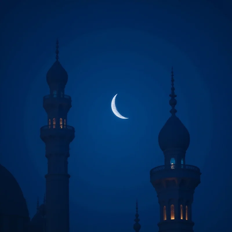 A crescent moon shining brightly in the night sky above a mosque minaret.