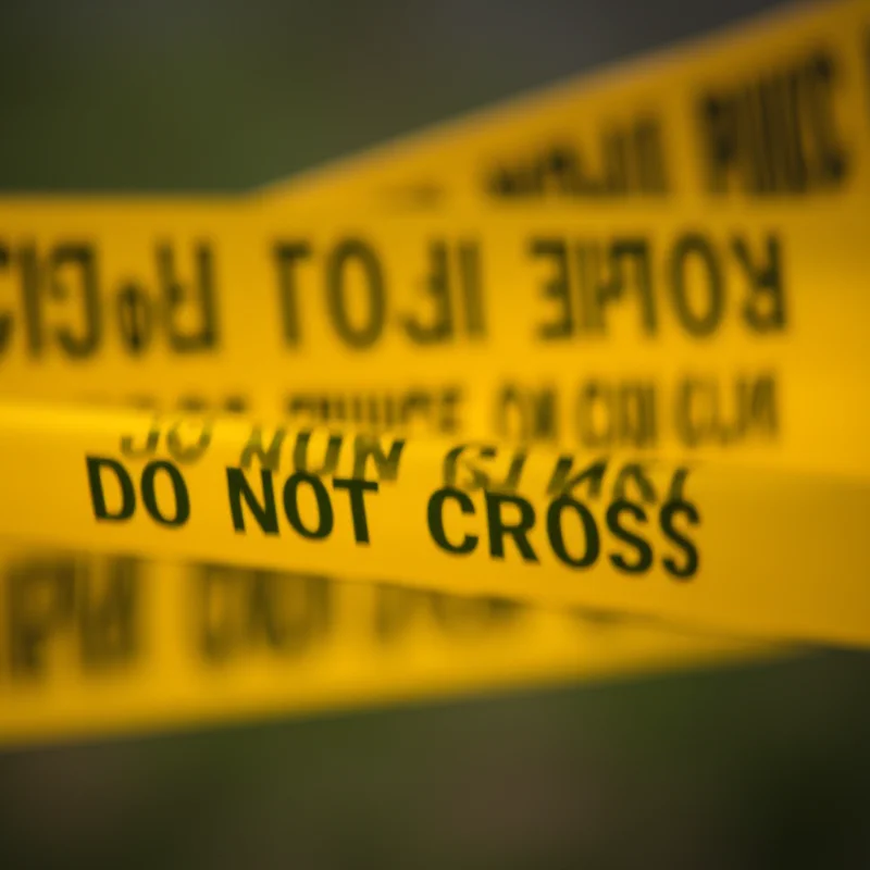 A close up of police tape with the words 'Crime Scene Do Not Cross' in bold yellow letters. 