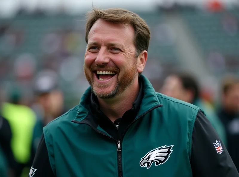 Howie Roseman smiling broadly on the sidelines of a football game, wearing an Eagles jacket.