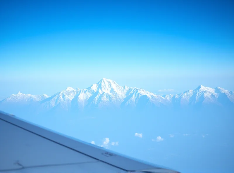 A panoramic view from an airplane window, showing Mount Everest and the surrounding Himalayan mountain range. The peaks are covered in snow and ice, and the sky is a clear blue. The wing of the airplane is visible in the foreground.