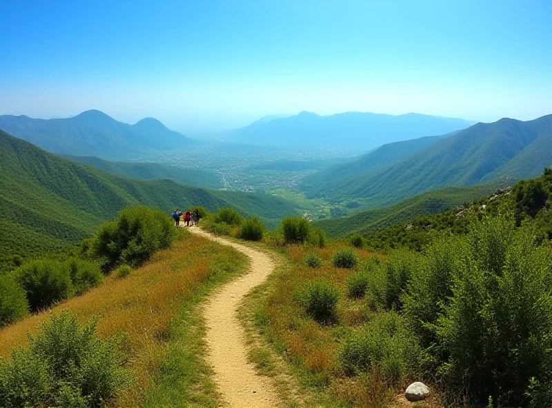 A panoramic view of the Albanian countryside, showcasing rolling hills and mountains under a clear blue sky. A winding hiking trail leads through the landscape, inviting exploration and adventure. The scene evokes a sense of peace and tranquility.