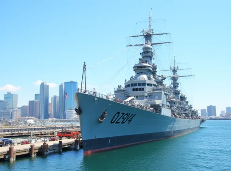 The USS Olympia docked in a harbor with the city skyline in the background.