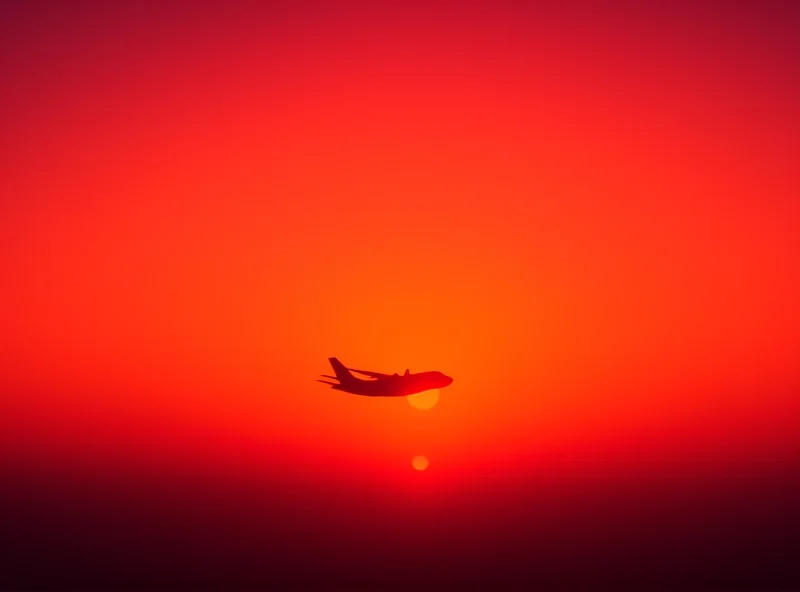 Silhouette of a military transport plane flying at sunset.