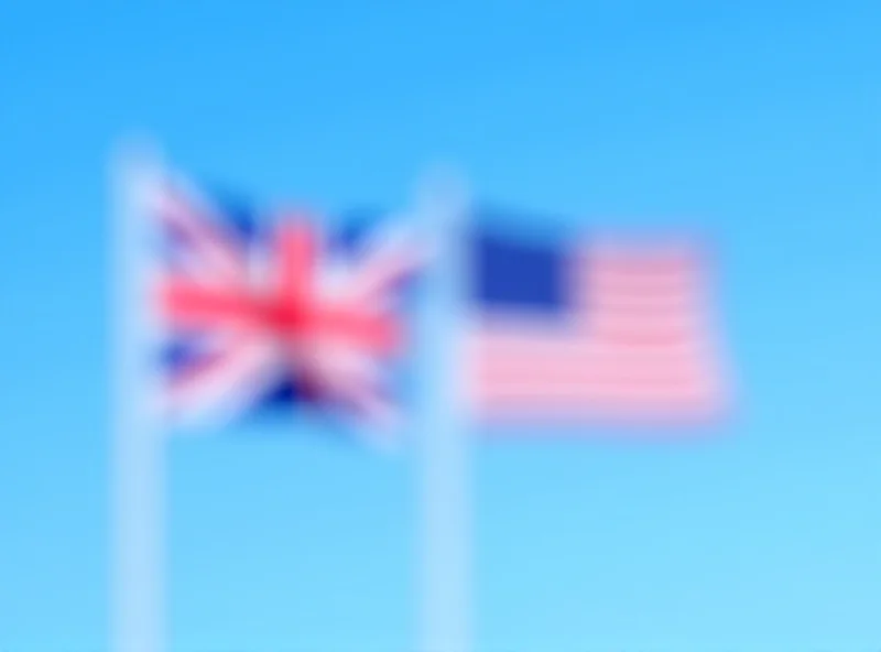 The flags of the United Kingdom and the United States waving side by side against a clear blue sky.