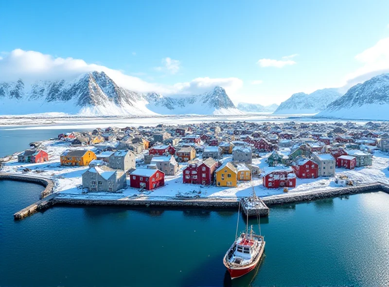 Aerial view of a colorful Greenlandic town nestled between mountains and the sea under a bright sunny sky.