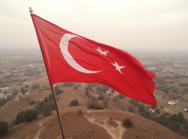 Aerial view of the Turkey-Syria border with a Turkish flag waving in the foreground and a Syrian city visible in the distance.