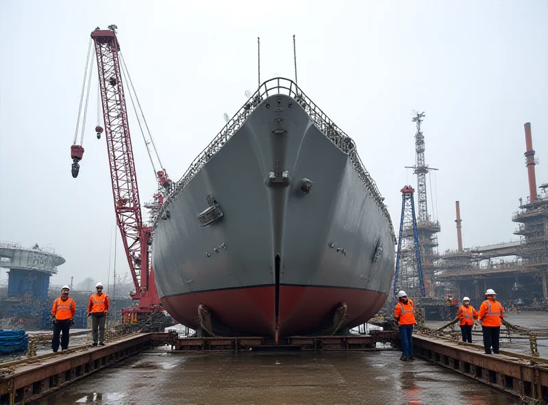 A large section of a warship's hull being lifted by a crane in a shipyard setting.