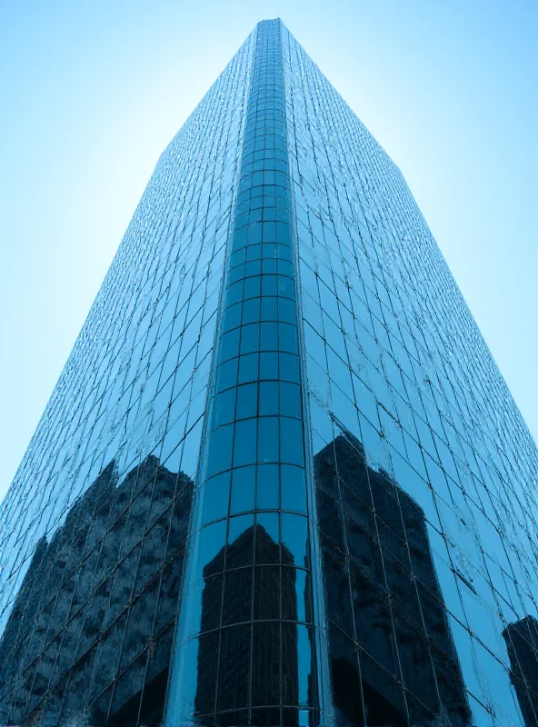 A modern skyscraper with glass windows reflecting a cityscape.